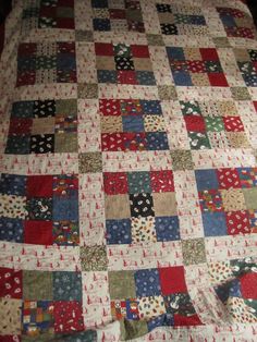 a quilt is laying on top of a bed with red, white and blue squares