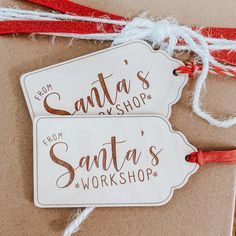 two wooden tags with the words santa's workshop on them