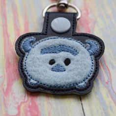 a close up of a keychain with a stuffed animal on it's face