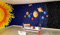 a room with solar system wallpaper and table in front of the space mural on the wall