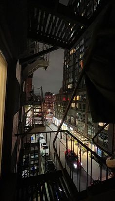 the view from an apartment balcony at night, looking down on a busy city street