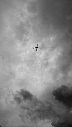 an airplane is flying high in the sky on a cloudy day with dark clouds behind it