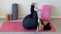 a woman is doing yoga on a pink mat with her legs up in the air