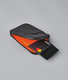 a black wallet with a credit card in it on a gray surface, and an orange light coming out of the pocket