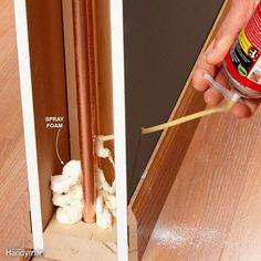 a person is holding a screwdriver in front of an open cabinet with wood flooring