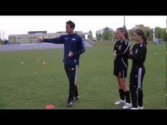 two women and a man standing on a soccer field