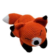 an orange knitted animal laying on top of a white surface