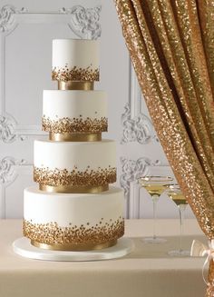 a white and gold wedding cake sitting on top of a table