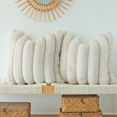 a bunch of white pillows sitting on top of a wooden shelf in front of a clock