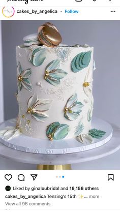 a wedding cake decorated with gold and green leaves