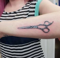 a woman with a tattoo on her arm holding a pair of scissors