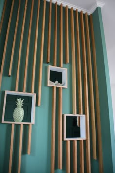 three pineapples are hanging on the wall with wooden slats behind them and framed photos