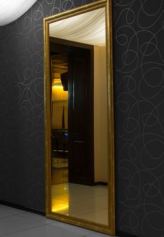 a large gold framed mirror sitting on top of a floor next to a black wall