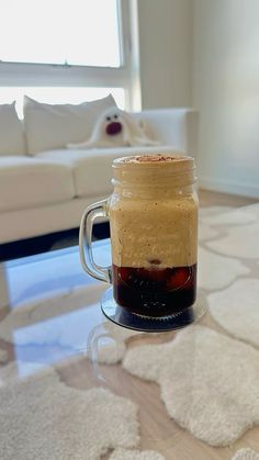 a coffee mug with liquid in it sitting on a table next to a white couch