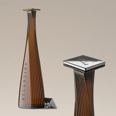 two tall vases sitting next to each other in front of a white background and one has a clock on the top