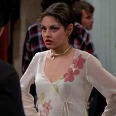 a woman in a white dress with flowers on it and a necklace around her neck