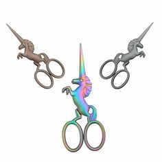 three metal scissors with different colored unicorns on them and one has an upside down handle