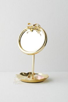 a small mirror with a bow on it sitting on top of a metal stand in front of a white wall