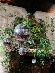 three disco balls hanging from the ceiling in front of a fire place with greenery