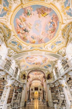 the interior of a library with many bookshelves and paintings on the ceiling above