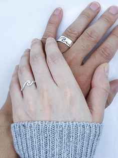 two hands holding each other while wearing rings