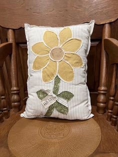 a pillow with a flower on it sitting on a chair in front of a wooden table