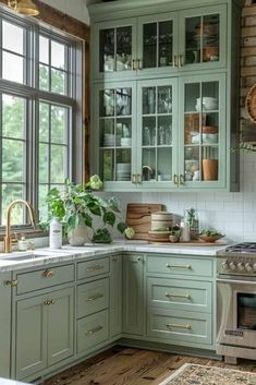 a kitchen filled with lots of green cupboards and counter top space next to a window