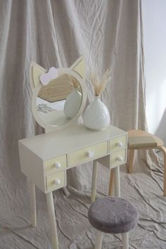 a white vanity with a mirror and stool