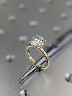 a close up of a diamond ring on top of a metal surface with screws