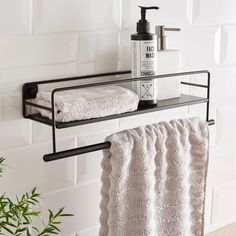 a towel rack with two towels and a bottle on it next to a potted plant