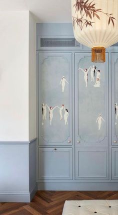 a room with blue painted cabinets and a white lamp hanging from the ceiling above it