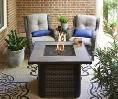 a patio with two chairs and a fire pit on the floor next to potted plants