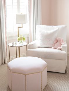 a pink and white living room with a teddy bear sitting on the chair next to it