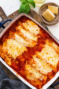 a casserole dish with cheese and sauce in it on a wooden tray next to some bread