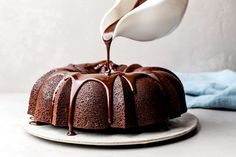 chocolate bundt cake being drizzled with icing on a white plate