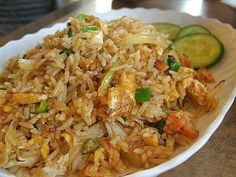 a white plate topped with rice and veggies next to a cucumber