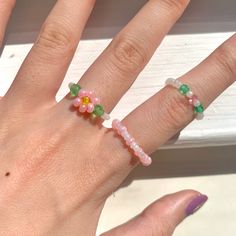 a woman's hand with three rings on her fingers and two flowers on the ring