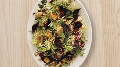 a white plate topped with salad on top of a wooden table