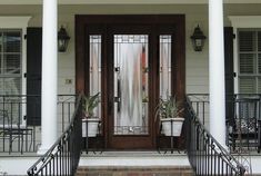 two potted plants sit on the front steps of a house with wrought iron railings