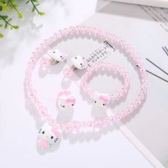 hello kitty necklace and bracelet set with pink beads on white table next to green plant