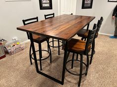 a kitchen table with four stools in front of it and a man standing next to it