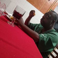 a man sitting at a red table with a glass of wine in front of him