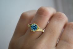 a woman's hand holding a ring with a blue topazte and diamond