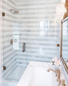 a bathroom with a glass shower door and marble counter top, along with a gold faucet