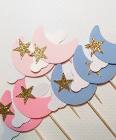 a bunch of cupcake toppers with gold stars and moon shapes on them sitting on a stick