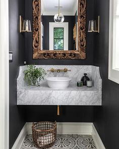 a white sink sitting under a mirror next to a bathroom vanity with a gold framed mirror above it