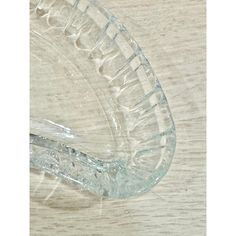 a clear glass bowl sitting on top of a wooden table next to a plastic spoon