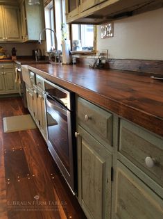 a kitchen with wood floors and cabinets in the center, along with a stove top oven