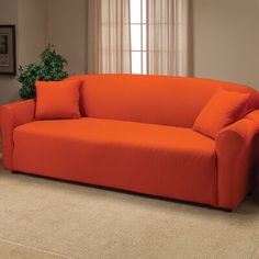 an orange couch sitting in a living room next to a lamp