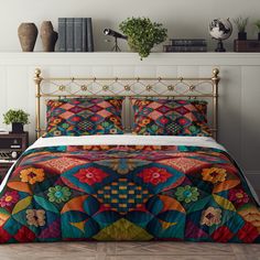 a bed with colorful quilts and pillows on it